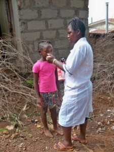 Nurse demonstrates to Hawanatu how to take the supplements