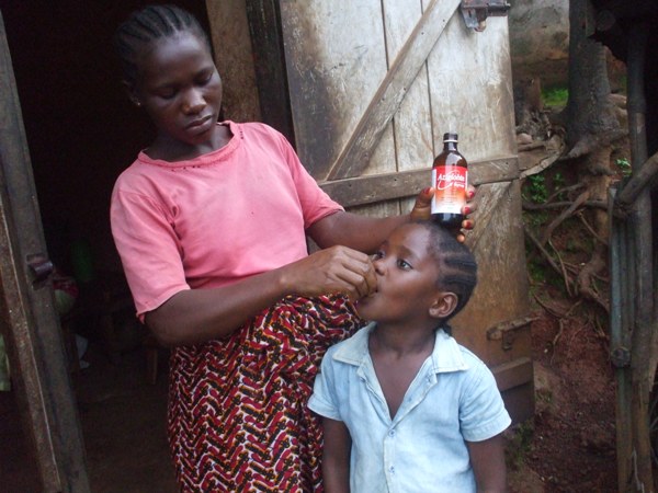 Yeabu - taking her vitamin supplements with the help of her mother